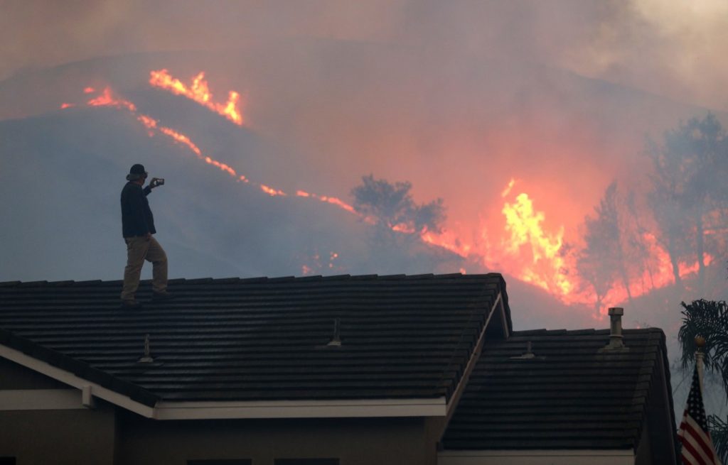 A person standing on the roof holding a camera 